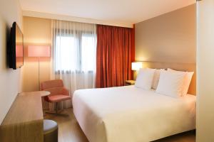 a hotel room with two beds and a lamp at Oceania Paris Roissy CDG in Le Mesnil-Amelot