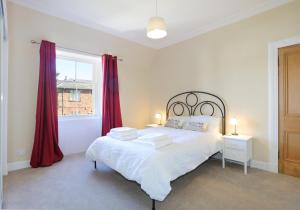 a bedroom with a bed with red curtains and a window at East Road Apartment in North Berwick