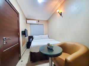 Habitación pequeña con cama, mesa y sofá. en Fadar's Place Hotel, en Sagisa