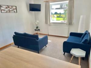 a living room with two blue couches and a tv at AIRDSIDE COTTAGE in Castle Douglas