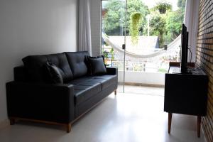 a black leather couch in a living room with a window at FLAT W3 Norte in Brasilia