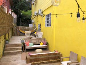 a patio with chairs and a hammock on a yellow building at Yellow Belly Backpackers in San Ignacio