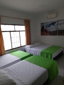 1 dormitorio con 3 camas con sábanas verdes en Hospederia Sol del Desierto, en Villavieja