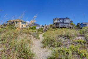 a group of houses on a beach with a path in the sand at SeaEscape in Folly Beach