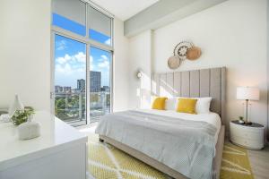 Dormitorio blanco con cama y ventana grande en Nomada Destination Residences - Quadro, en Miami