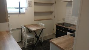 Elle comprend une petite cuisine avec une table en bois et un bureau. dans l'établissement Mieszkanie, à Kołobrzeg