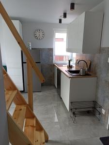 una cocina con armarios blancos, un lavabo y una escalera en Agroturystyka u Basi, en Wola Kalinowska