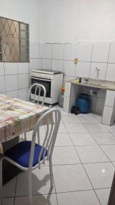 a kitchen with a table and a chair and a stove at Minha casa fora de casa in Jandira