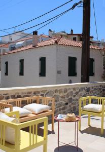 three chairs and tables on a patio with a building at Aeonian Villa Ermioni in Ermioni