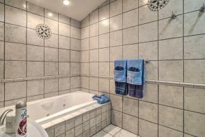 a white tiled bathroom with a tub and blue towels at Home on Douglas Lake - Fish and Kayak! in Dandridge +24 photos