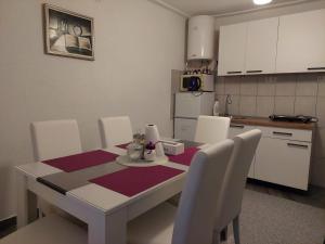 una cocina con mesa blanca, sillas blancas, mesa y sillón en Apartman Amelaa en Kulen Vakuf
