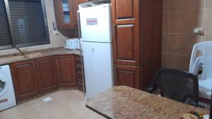 a kitchen with a white refrigerator and wooden cabinets at Cool Bayader apartment in Amman