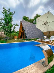 a swimming pool with a large umbrella and a house at SAPANCA BUNGALOVCA in Sapanca