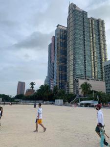 a group of children walking on a beach with tall buildings at Grand Riviera Suites Comfy Condo near US Embassy Manila Bay Roxas Blvd Ermita Manila in Manila
