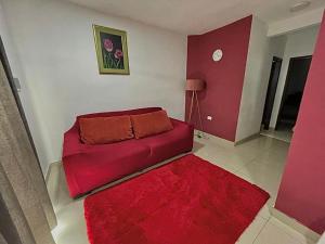 sala de estar con sofá rojo y alfombra roja en Departamento entero, en Asunción