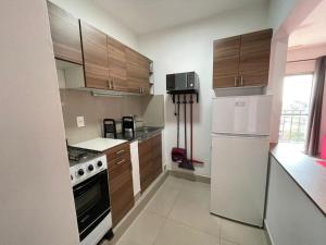 cocina con armarios de madera y nevera blanca en Departamento entero, en Asunción