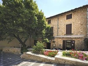 a brick building with a tree in front of it at Logis Hôtel Restaurant Les Géraniums in Le Barroux