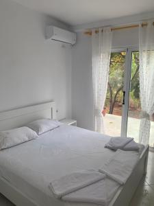 a white bed in a bedroom with a window at Loft Apartments in Sarandë
