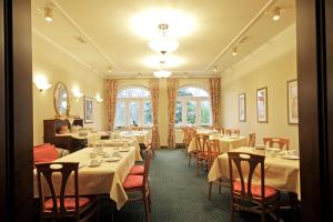 une salle à manger avec des tables blanches, des chaises et des fenêtres dans l'établissement Parkhotel Oybin, à Kurort Oybin