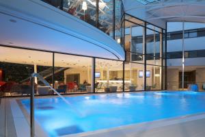 a large swimming pool with a large glass door at Oceania Paris Roissy CDG in Le Mesnil-Amelot