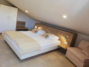 a bedroom with a large bed and a chair at Haus Mit Meerblick in Lopar