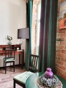 W salonie znajdują się zielone zasłony, stół i biurko. w obiekcie Nowy Rynek 10 w mieście Płock