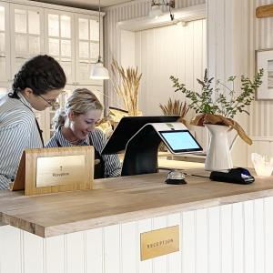 Dos mujeres de pie en un mostrador con caja registradora en Eco by StrandNära, en Mörbylånga