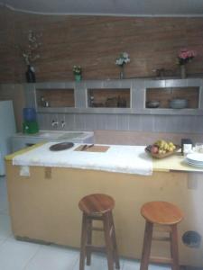 um balcão de cozinha com dois bancos e uma taça de fruta em Sítio Porta das Águas em Caxambu
