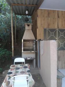uma cozinha exterior com uma mesa e um forno em Sítio Porta das Águas em Caxambu