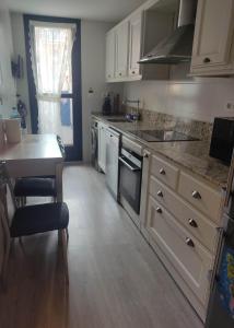 cocina con armarios blancos y encimera en Precioso apartamento con terraza, pistas de padel y piscinas, en Castro Urdiales