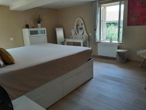 1 dormitorio con 1 cama blanca grande y espejo en Logement Confortable dans résidence privée, en Amplepuis