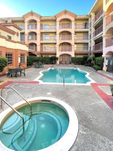 a pool in front of a large apartment building at Ramada by Wyndham South El Monte in South El Monte