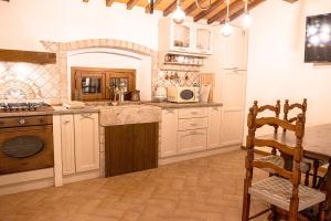 uma cozinha com armários brancos, uma mesa e uma cadeira em Casa alle Monache em Gambassi Terme