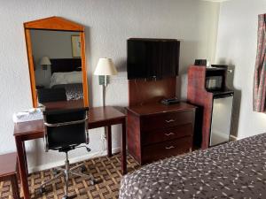 Habitación de hotel con cama, escritorio y espejo. en Budget Inn, en Tallahassee