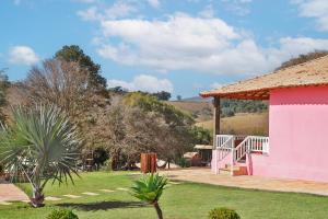 una casa rosa con una puerta blanca y un patio en Paraíso Rural, en São Thomé das Letras