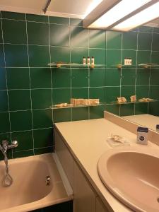 Baño de azulejos verdes con lavabo y bañera en House City Bari, en Bari