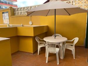 Biały stół z krzesłami i parasolem w obiekcie Apartamento renovado en Puerto de la Cruz w Puerto de la Cruz