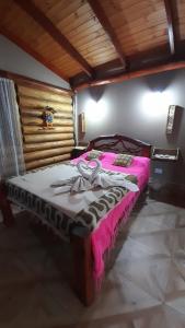a bedroom with a bed with a pink blanket at Hotel y Cabañas Green Park in Nono