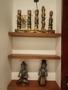 a shelf with a group of figurines on it at The Kd Suites & Coffee Shop in Munggu