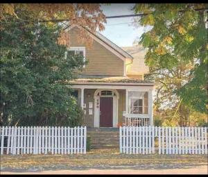 una casa gialla con una recinzione bianca davanti di Suede a Salem