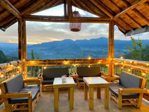a porch with chairs and tables and a view of mountains at Hass Glamping Jericó in Jericó