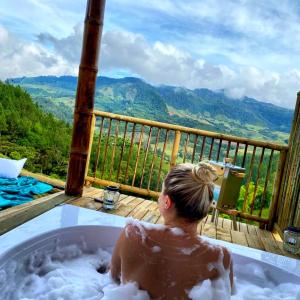 a woman sitting in a bath tub with a view at Hass Glamping Jericó in Jericó