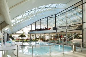 - une grande piscine dans un bâtiment doté d'un plafond en verre dans l'établissement Oceania Paris Roissy CDG, au Mesnil-Amelot