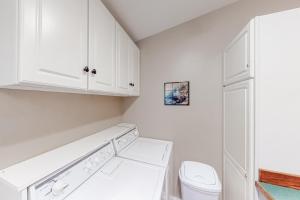 a white laundry room with a toilet and white cabinets at Getaway on Mariposa in Hailey +15 photos