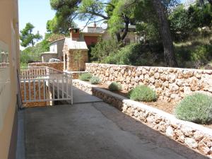 a stone retaining wall and a walkway in front of a house at Apartment Sveta Nedilja 14086a in Jelsa