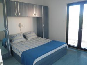 a bedroom with a bed with blue sheets and a window at Apartments with a parking space Lopar, Rab - 14089 in Lopar
