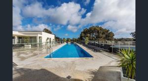 a swimming pool with chairs next to a house at Luxury 2 Bedroom Suite near Adelaide with a car park in Broadview