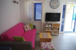 a living room with a pink couch and a tv at Apartments by the sea Slatine, Ciovo - 14158 in Slatine