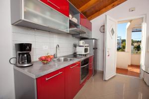 uma cozinha com armários vermelhos e um lavatório em Apartments with a swimming pool Preko, Ugljan - 14163 em Preko