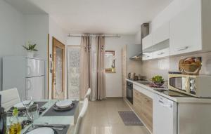 a kitchen with white appliances and a dining table at Family friendly apartments with a swimming pool Vodnjan, Fazana - 14159 in Vodnjan